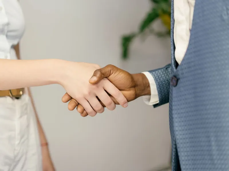 Aperto de mãos entre duas pessoas fechando uma parceria